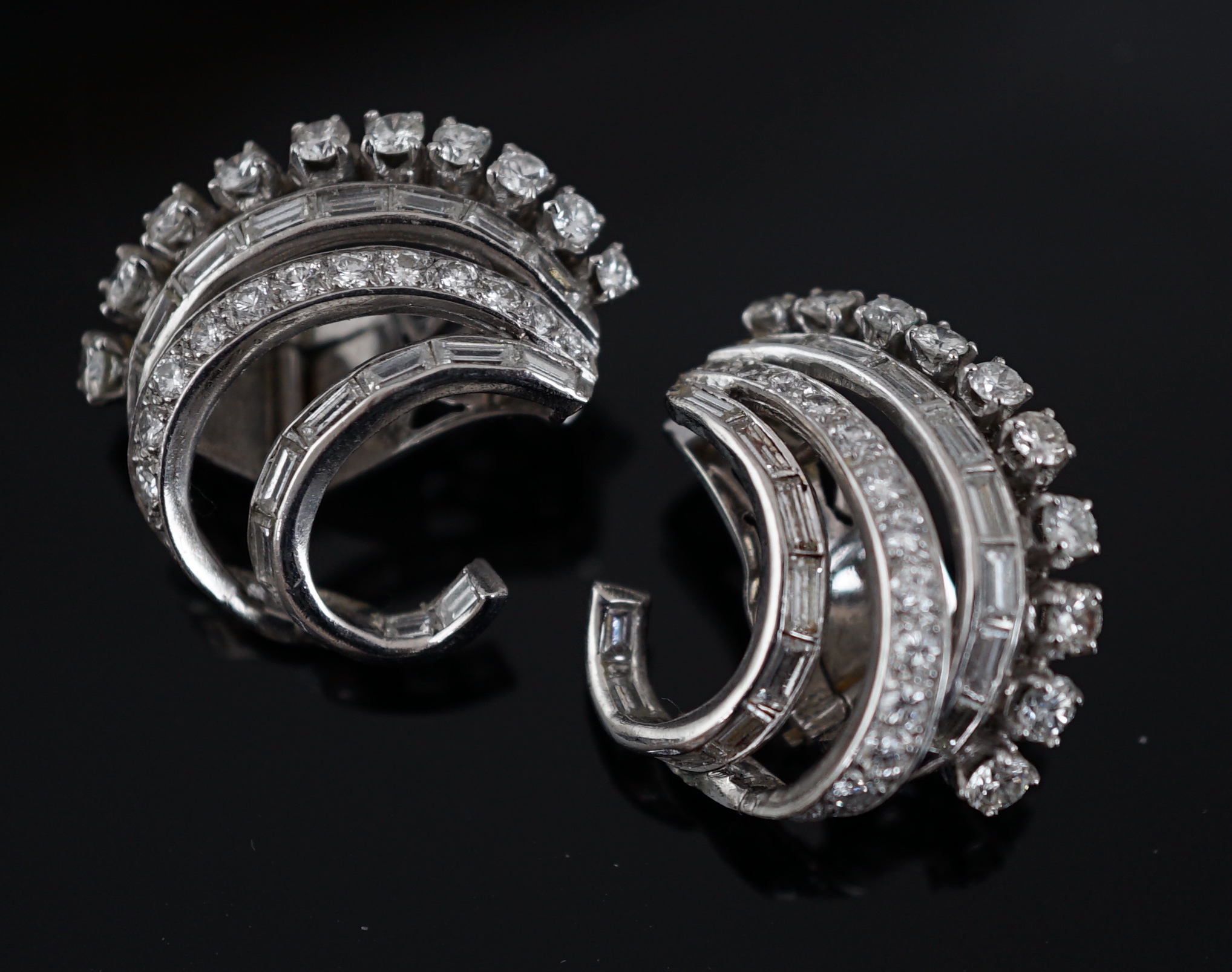 A pair of platinum? and diamond cluster set scrolling earrings